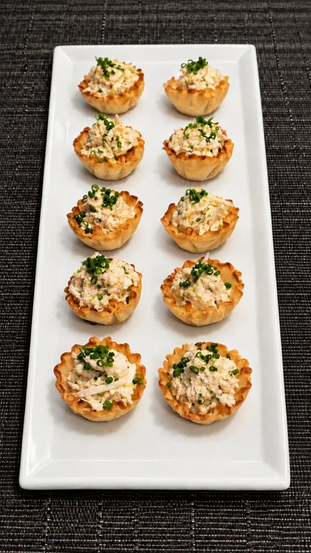 Small pastry cups with colourful toppings arranged on a white platter.