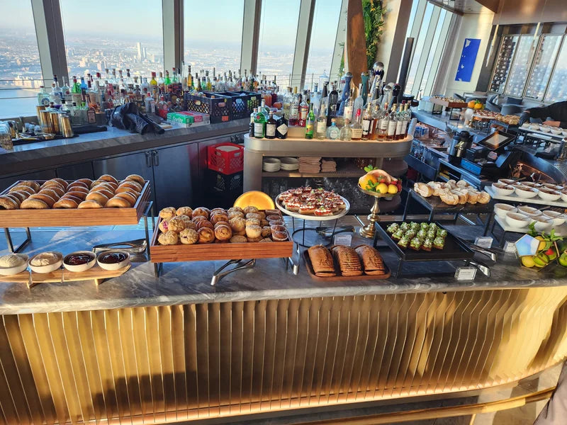 A breakfast buffet in front of large windows overlooking the city.