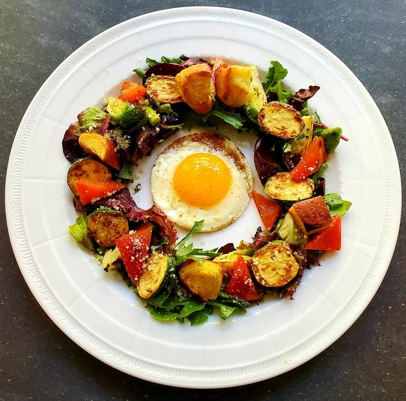 A colourful composed plate with an egg at its centre.